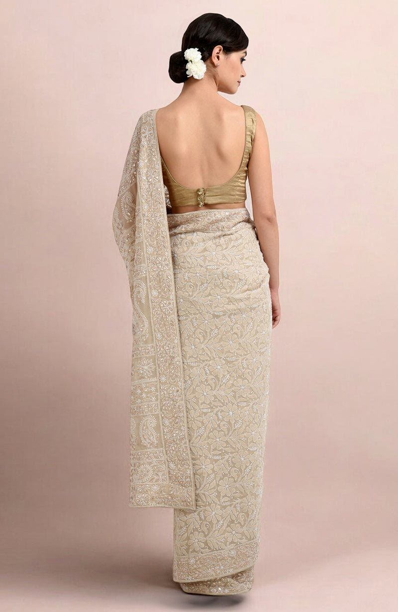 A woman from behind wears a champagne chikankari saree with a gold blouse.