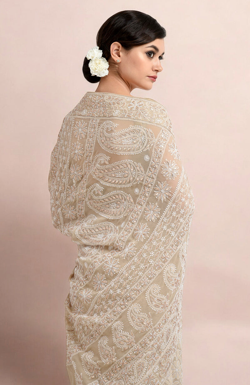 A woman models a champagne Lucknowi Chikankari and Gota Patti hand-embroidered saree.