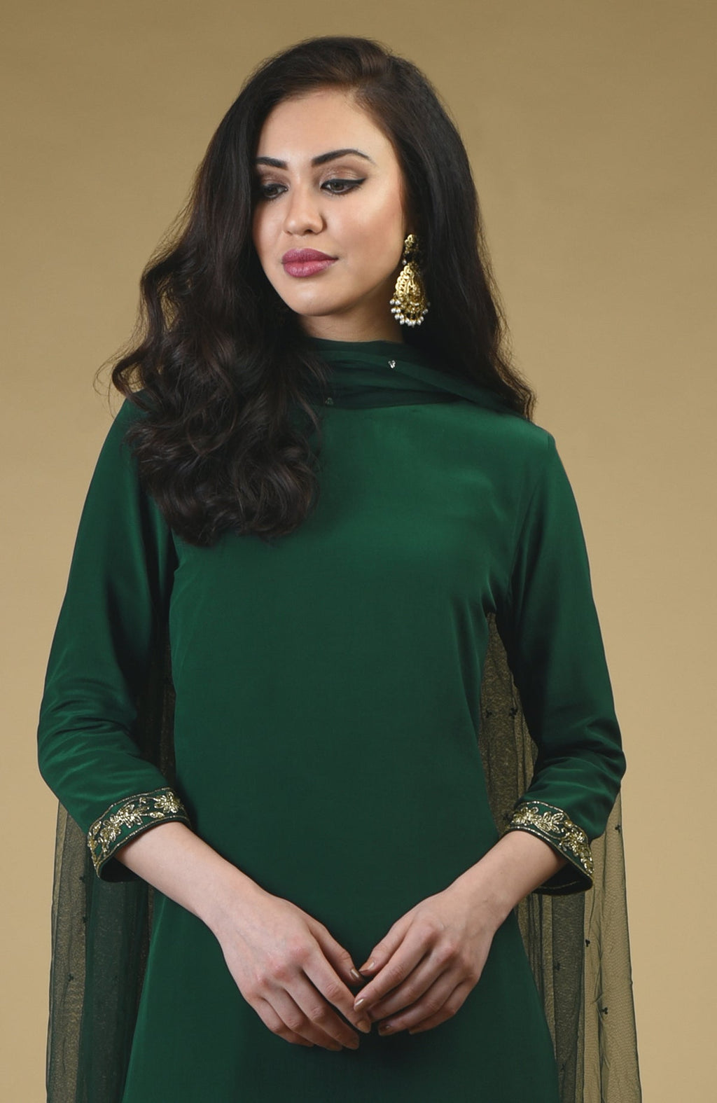 An emerald green sharara suit with gold embroidery on the sleeves and a sheer dupatta.