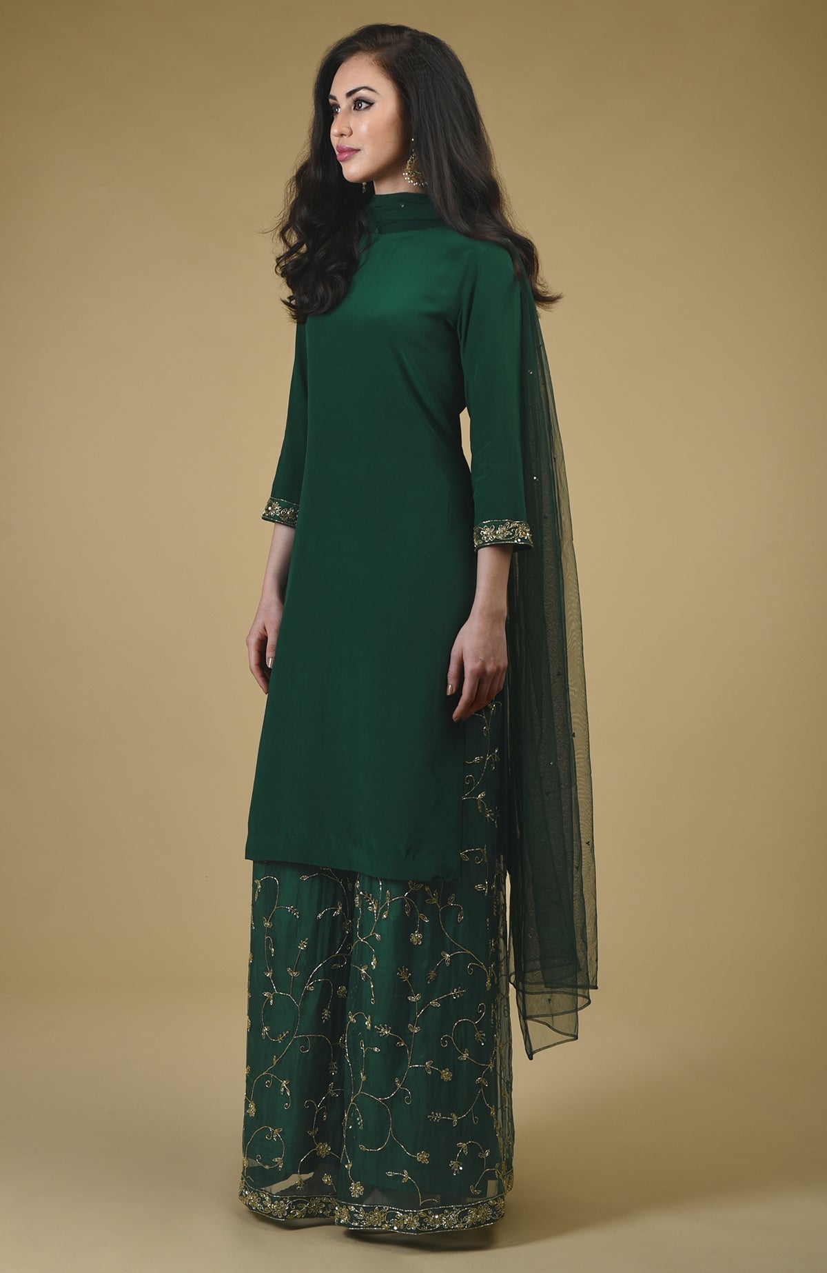 An emerald green sharara suit with gold zardozi hand embroidery.