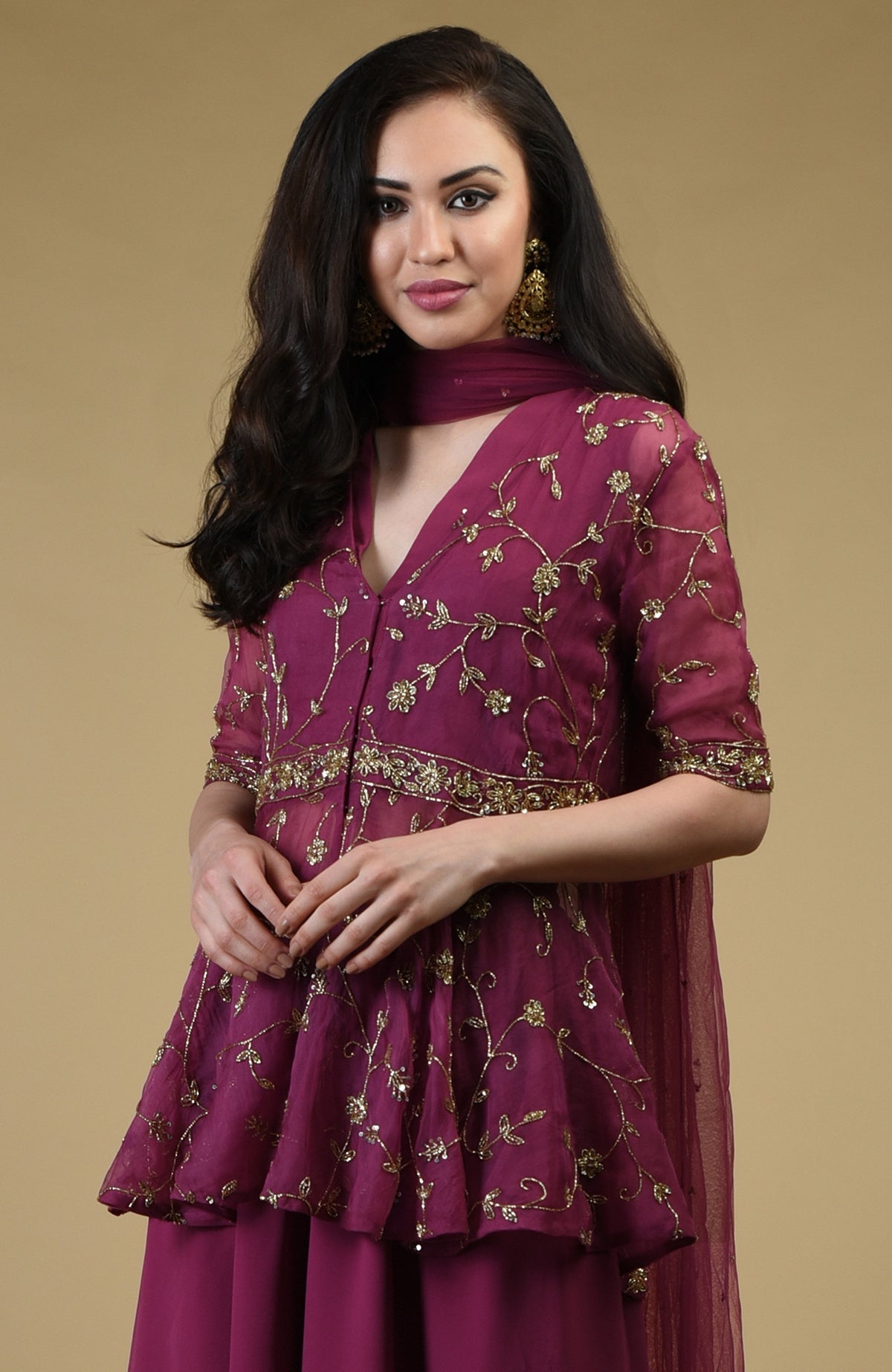 A woman models a peacock pink sharara suit with gold embroidery.