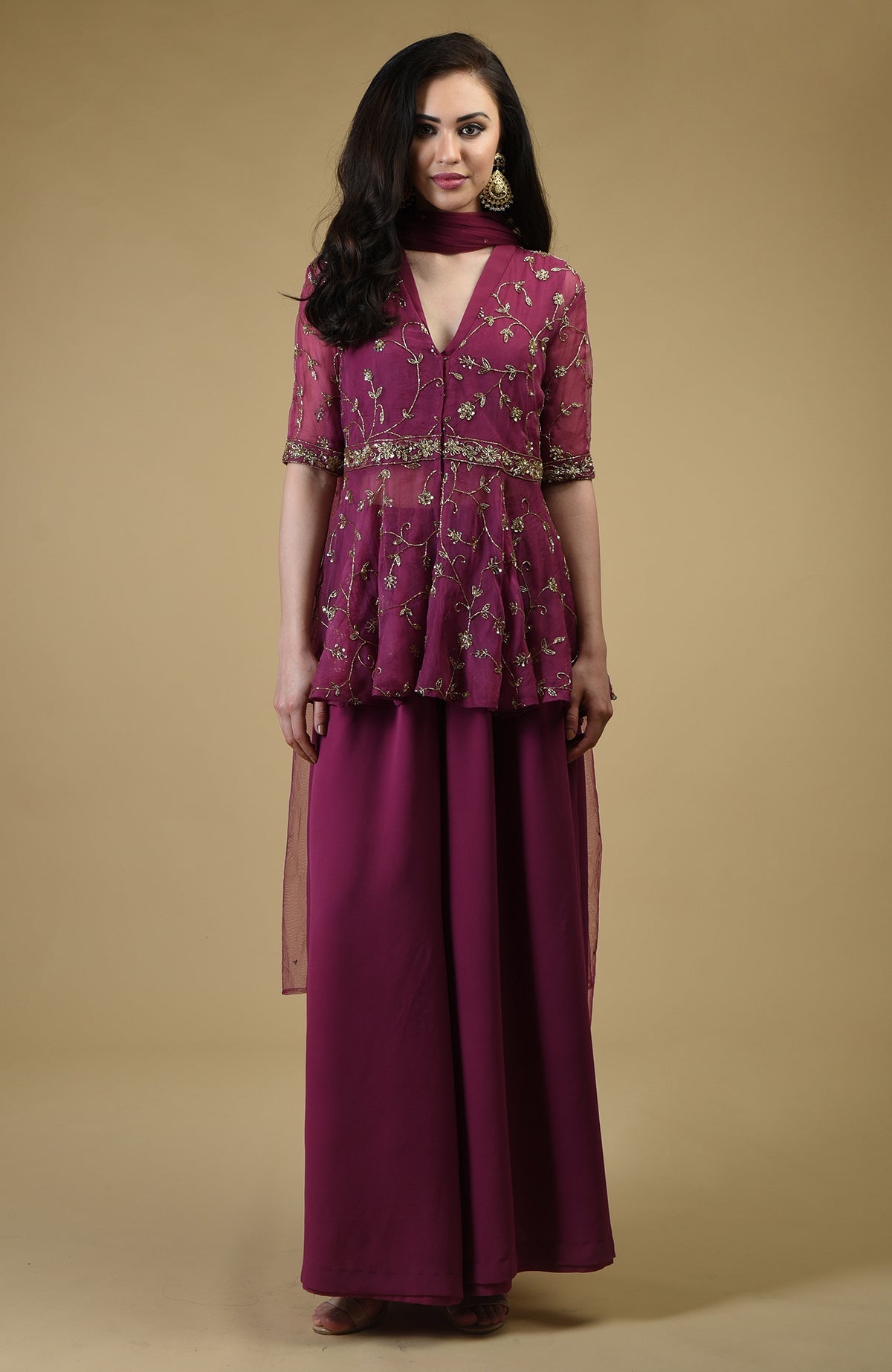A woman models a peacock pink sharara suit with gold embroidery.