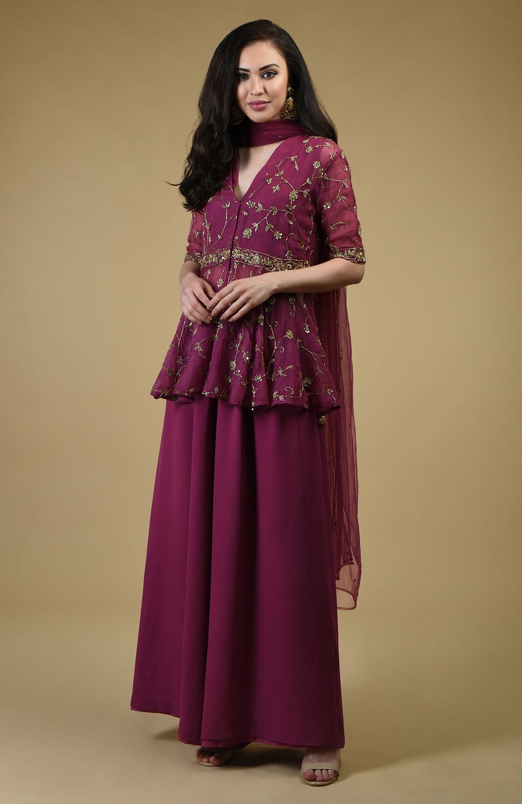 A woman models a peacock pink sharara suit with gold embroidery.