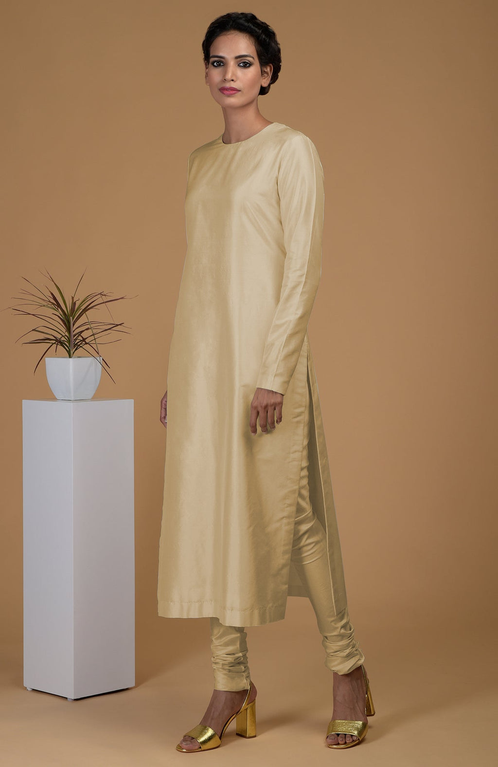 A woman models a beige pure Matka silk kurta set with golden heels.