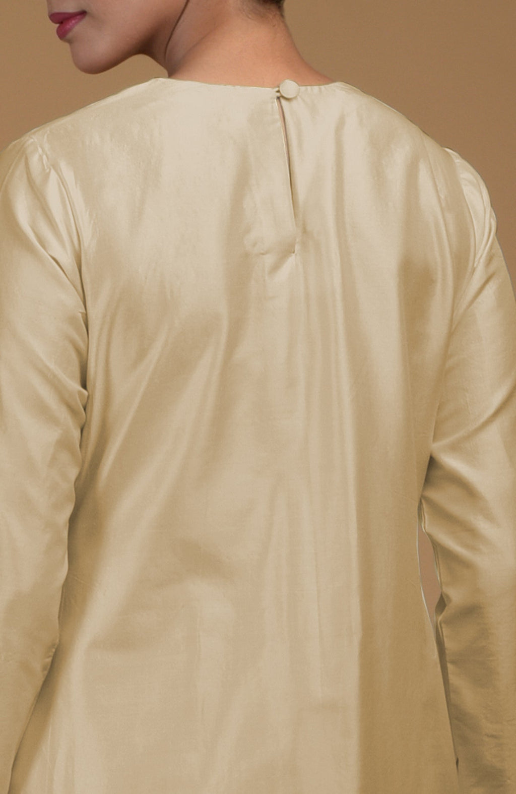 A woman models a beige pure Matka silk kurta with a jewel neck and keyhole back.