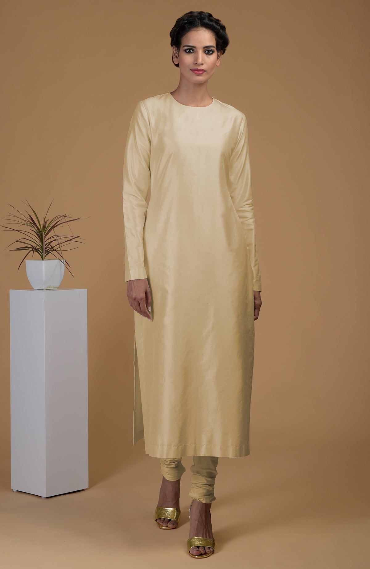 A woman models a beige pure Matka silk kurta set with a jewel neck.