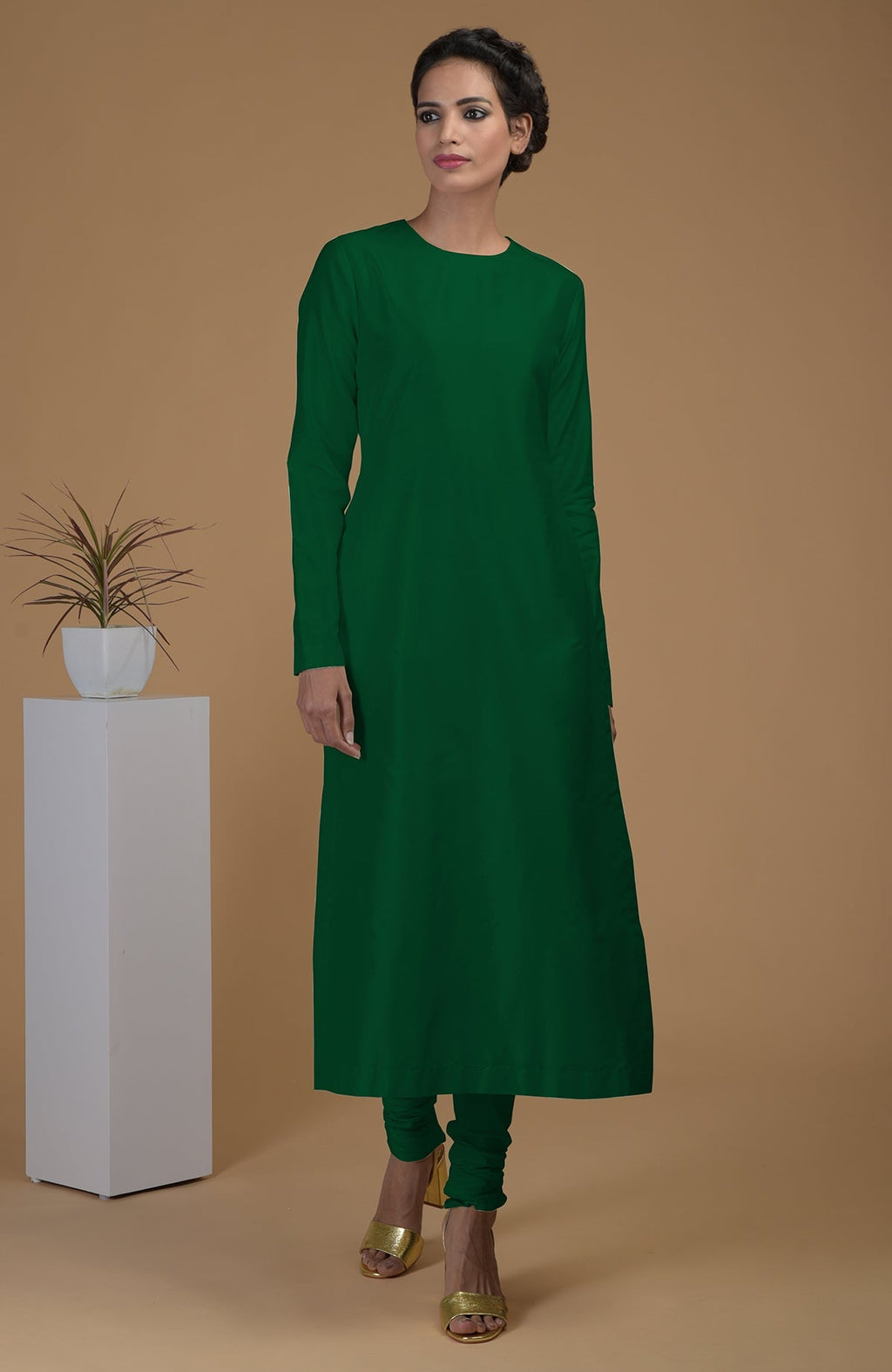 An emerald green pure Matka silk kurta set with a jewel neck and churidars.