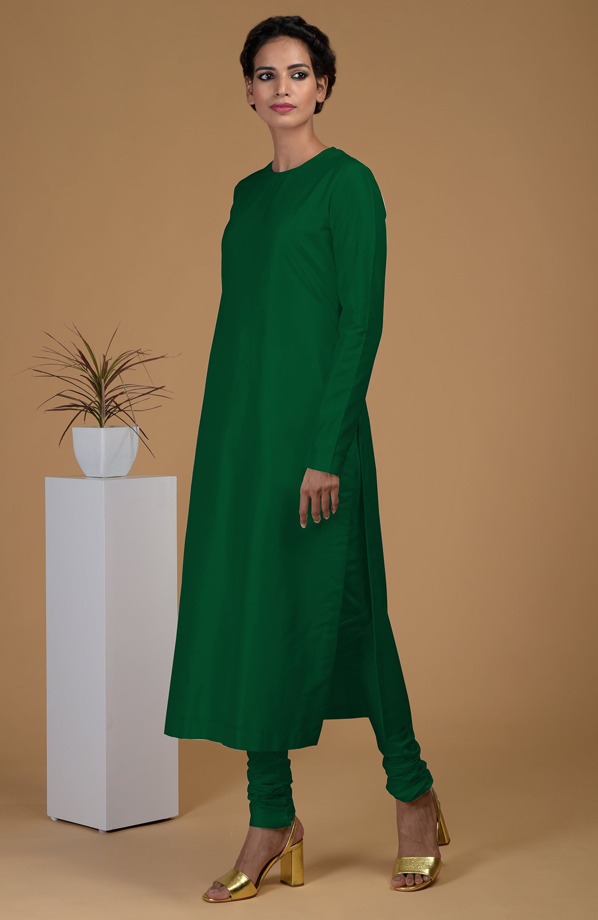 An emerald green pure Matka silk kurta set is modeled against a tan background.