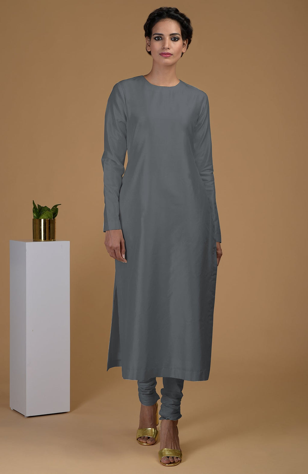 A woman models a grey pure Matka silk kurta set with golden heels.