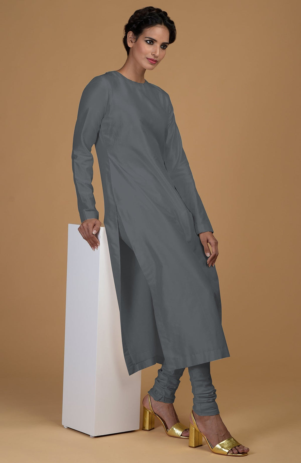 A woman models a grey pure Matka silk kurta set with golden heels.
