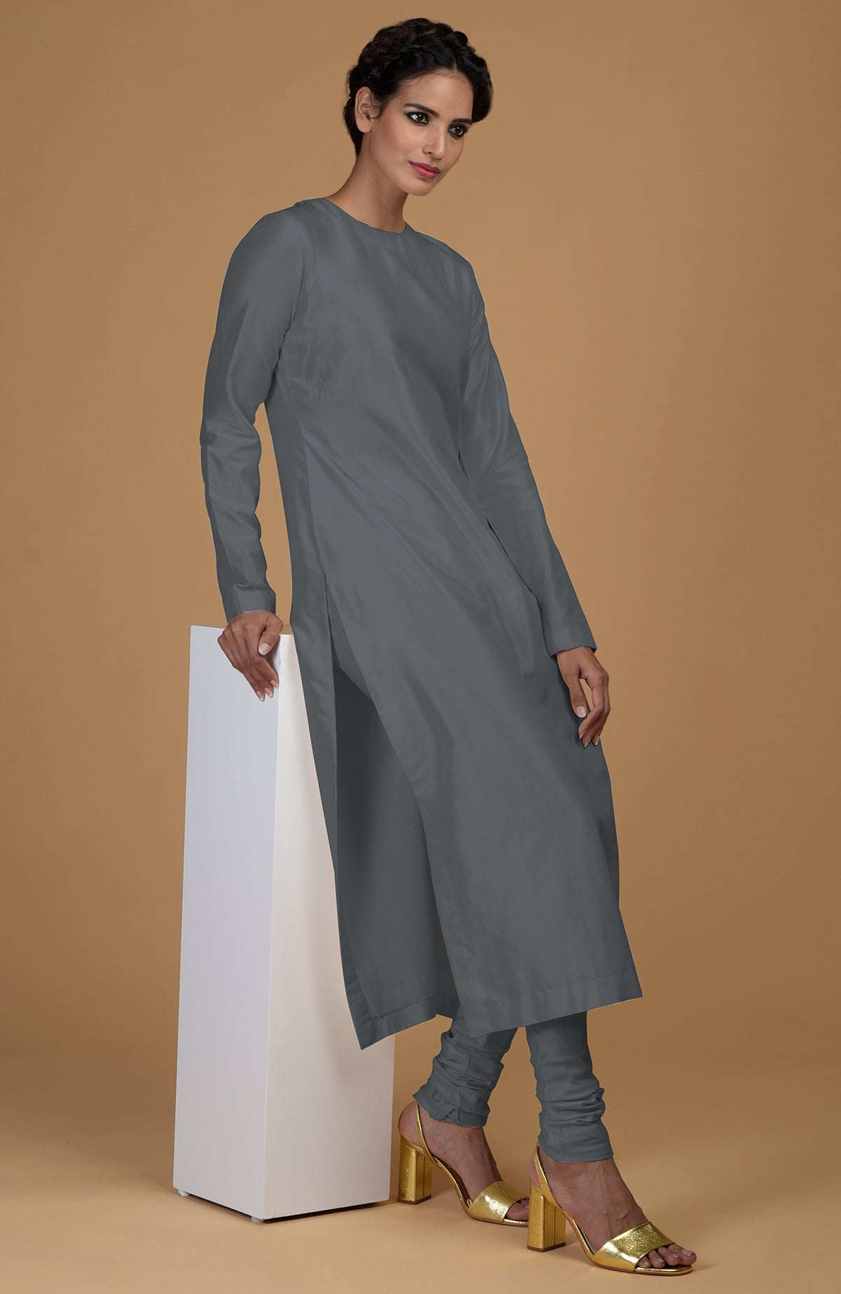 A woman models a grey pure Matka silk kurta set with golden heels.