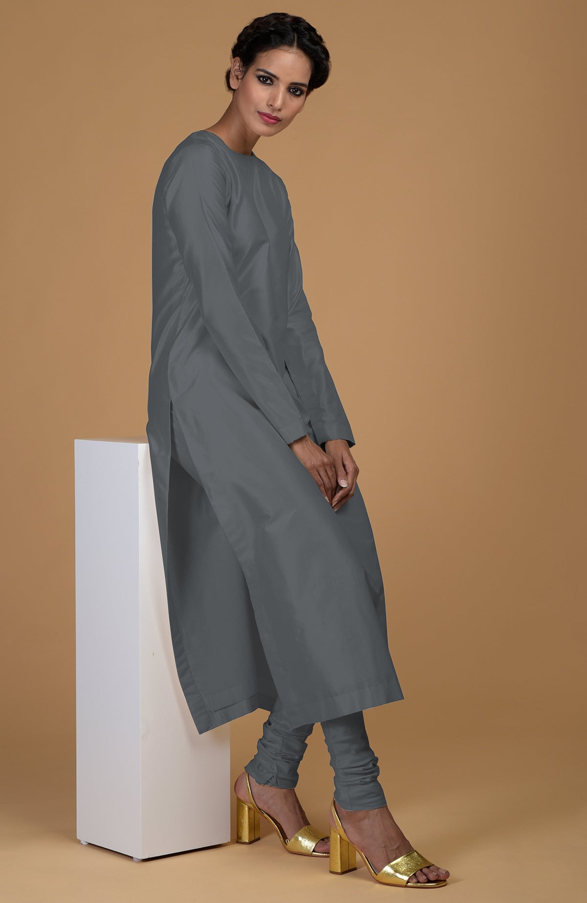 A woman models a grey pure Matka silk kurta set with gold heels.