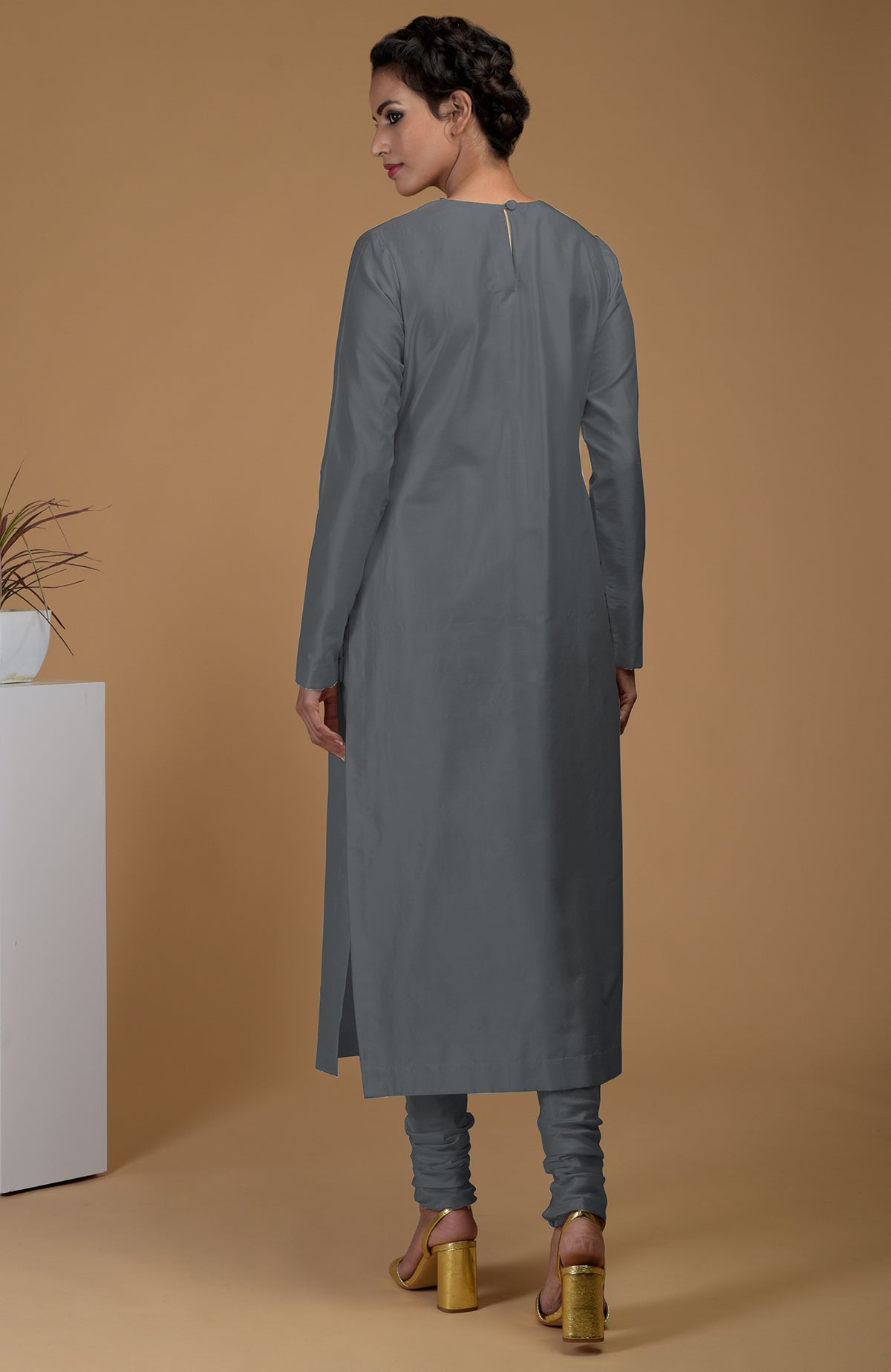 A woman models a grey pure Matka silk kurta set with a jewel neck and churidars.