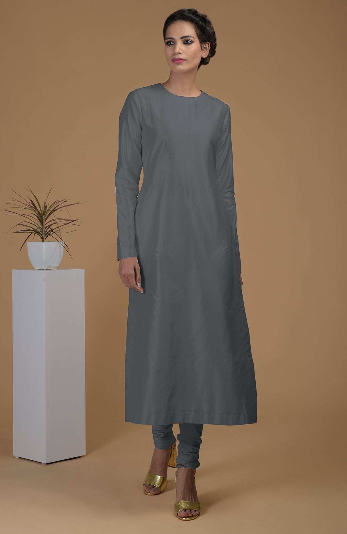 A woman models a grey pure Matka silk kurta set with gold heels.