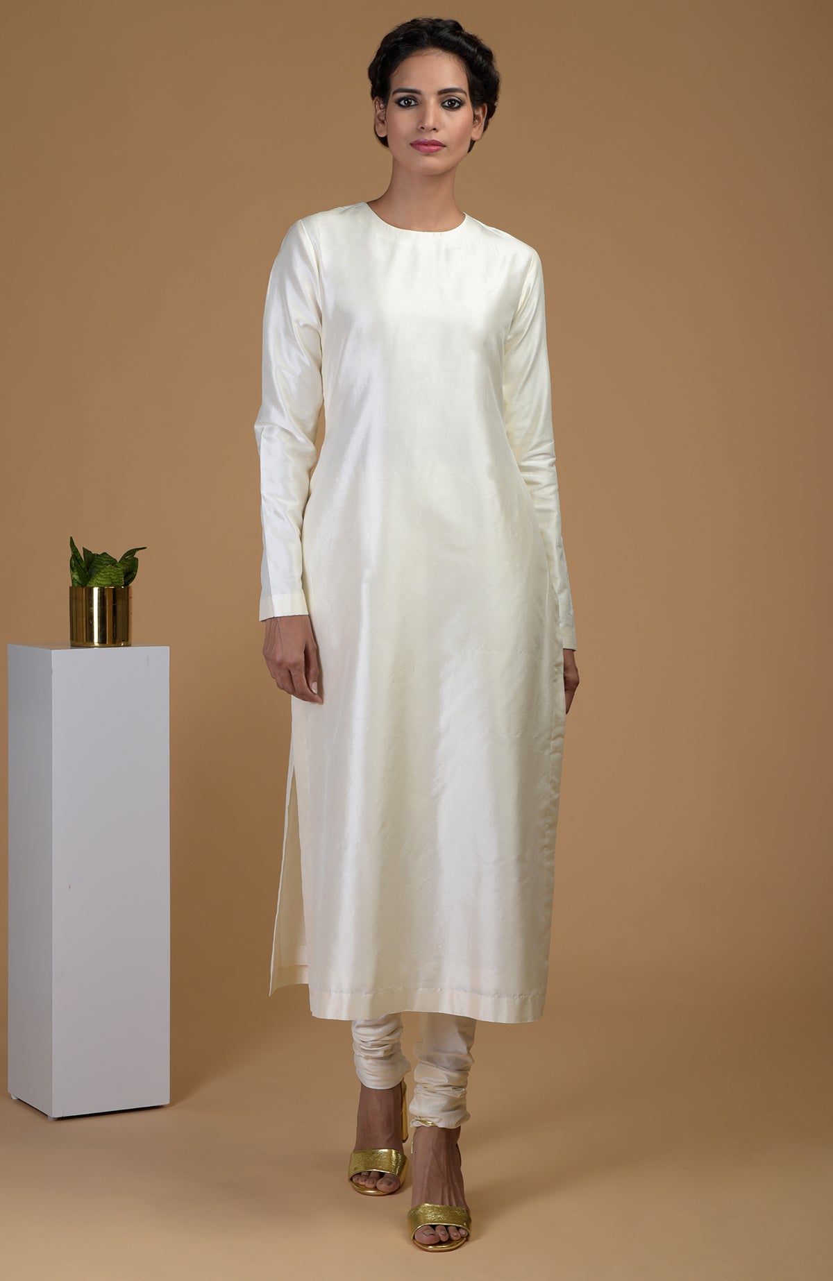 An ivory pure Matka silk kurta set with a jewel neck and churidar pants.