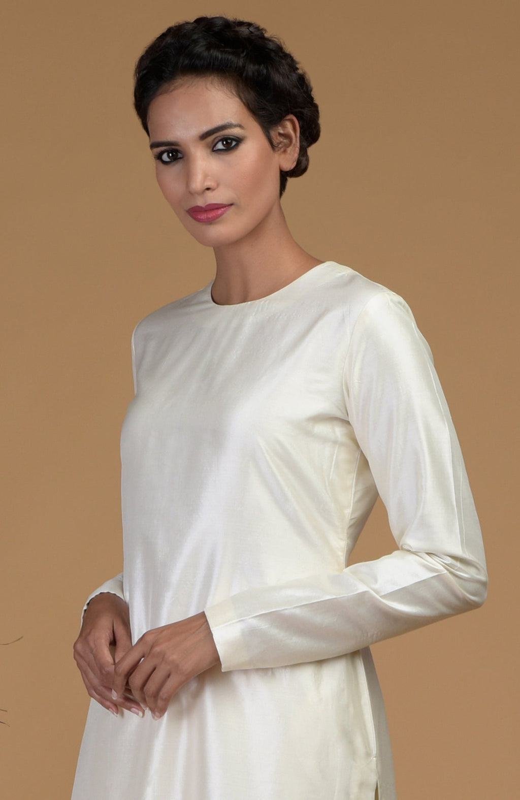 An Indian woman models an ivory pure Matka silk jewel neck kurta set.