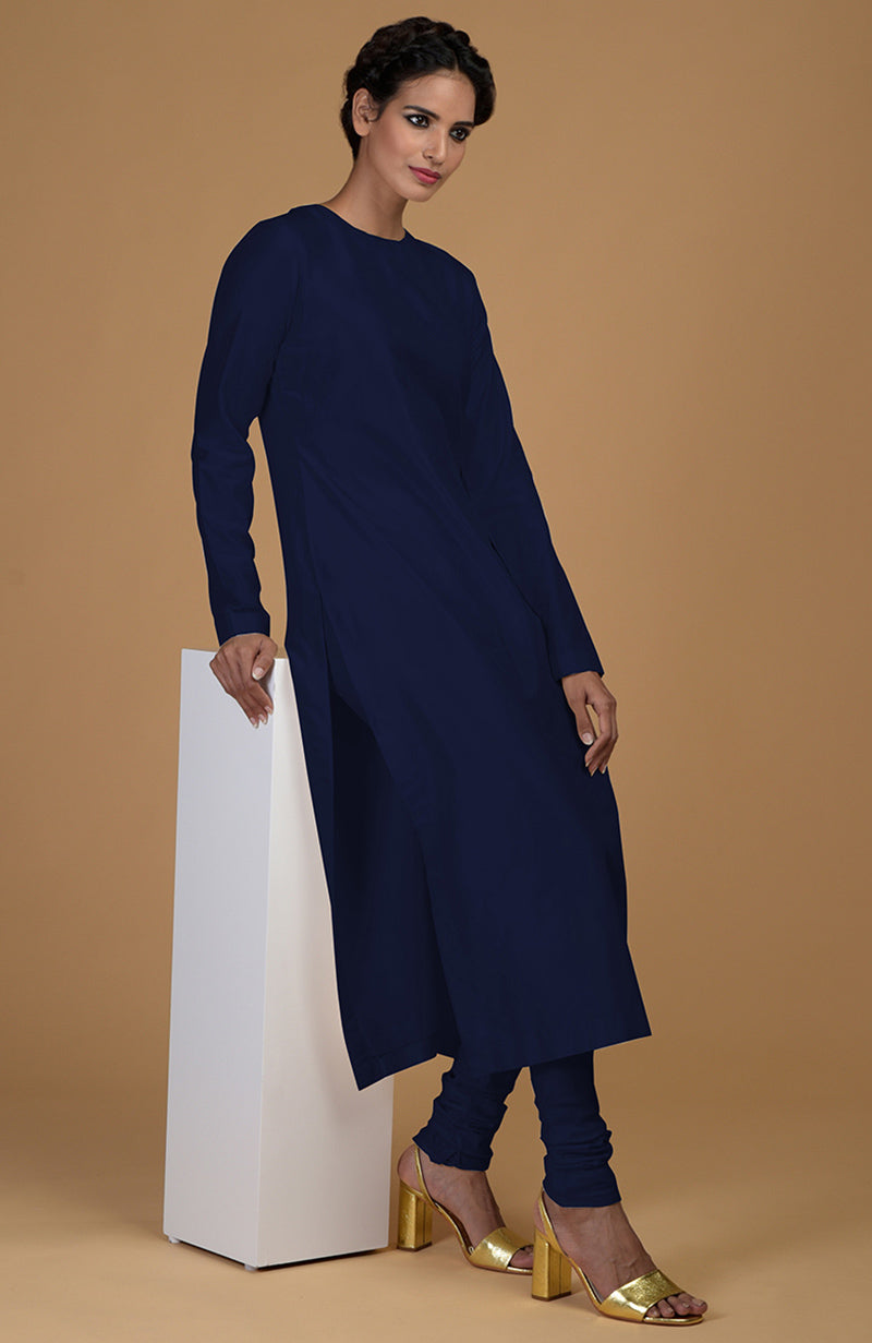 A woman in a navy blue kurta with side slits and matching churidars, posing with a white block.