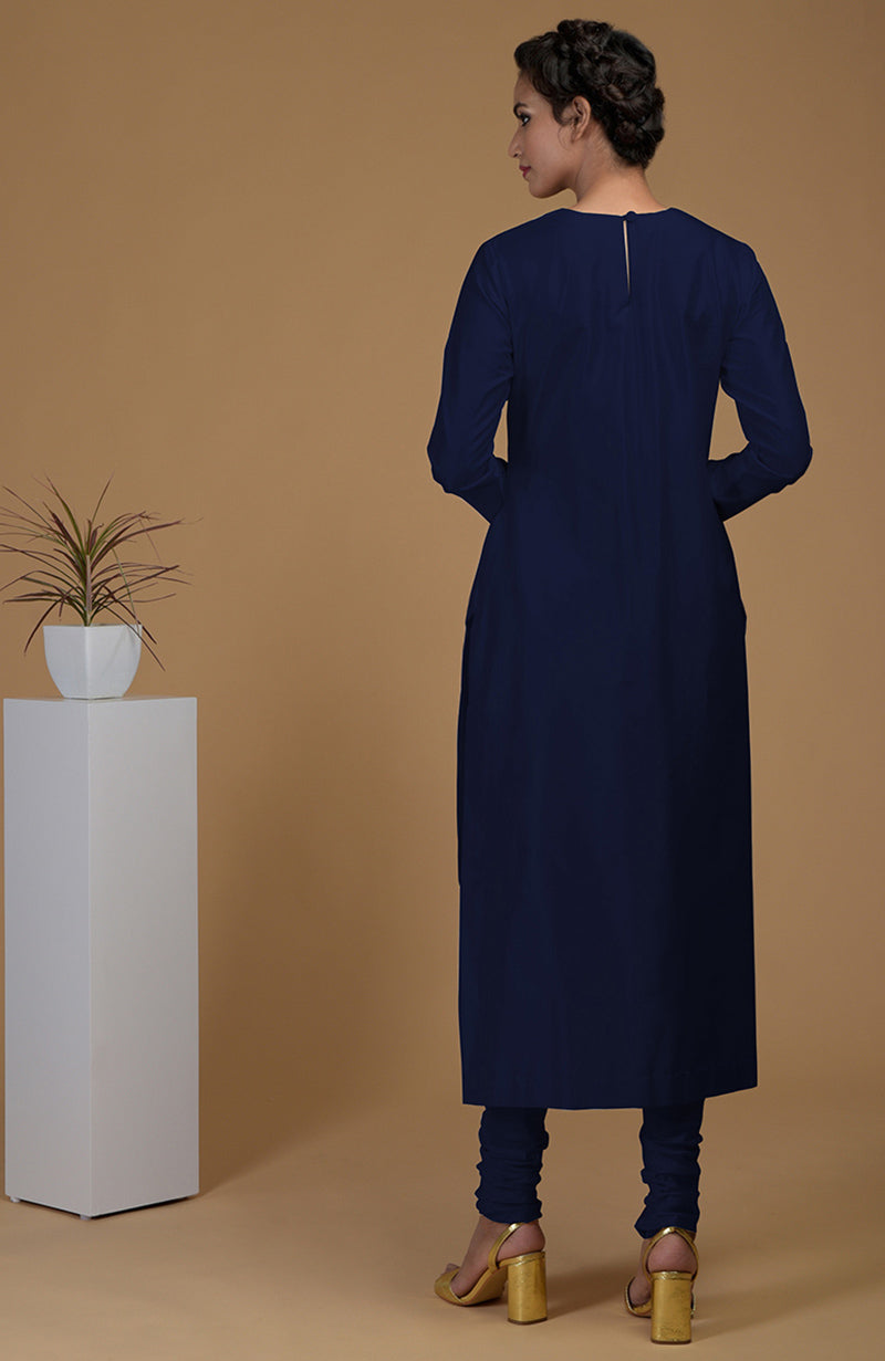 A woman models a navy blue pure Matka silk kurta set with gold heels.