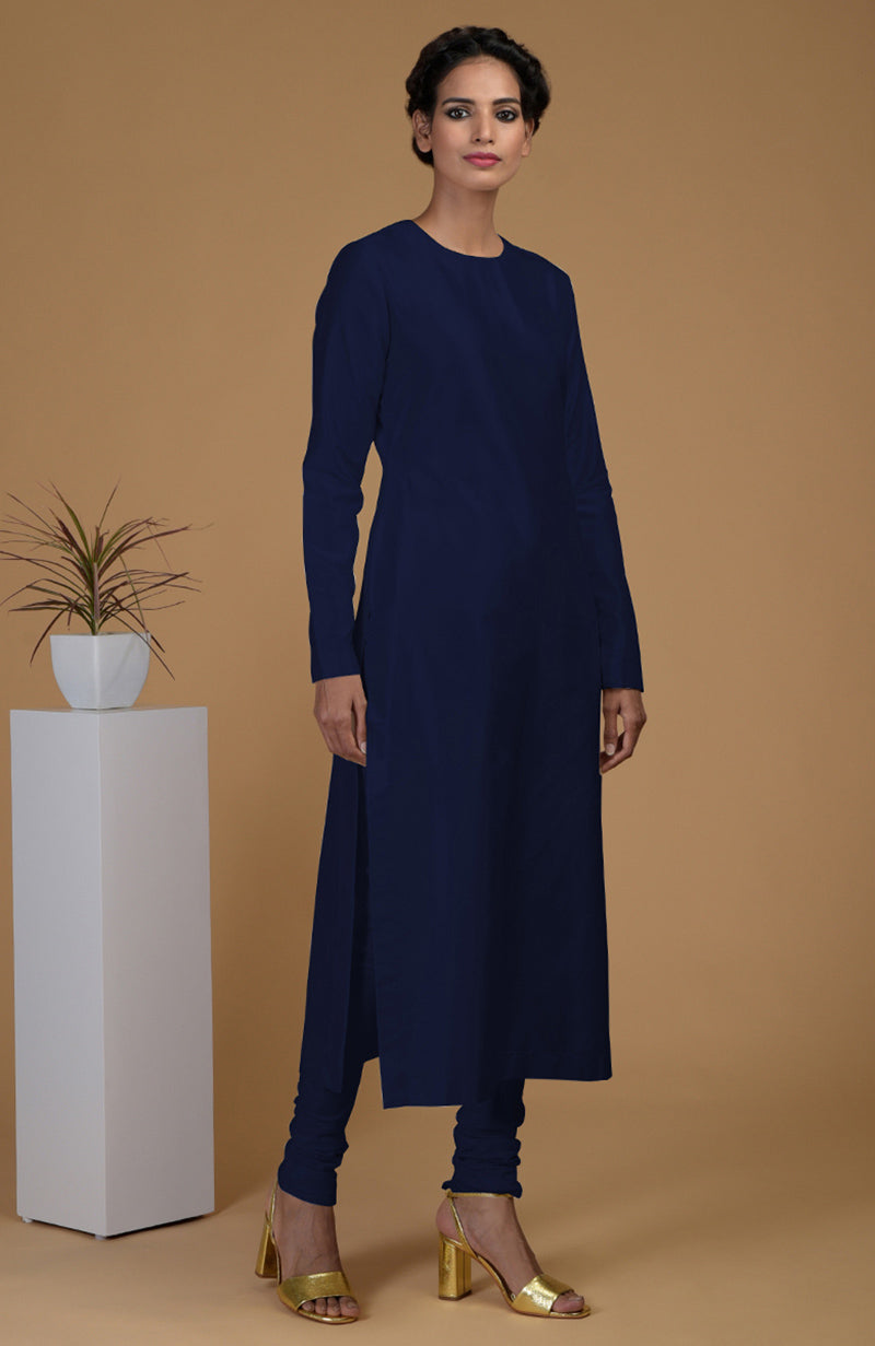 A woman models a navy blue pure Matka silk kurta set with gold heels.