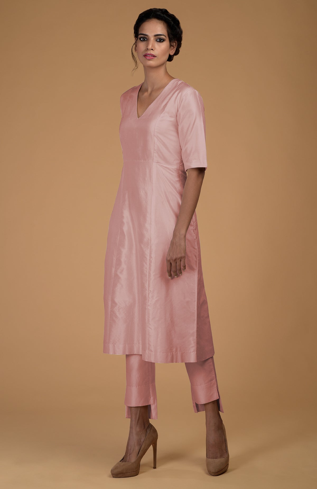 A woman models a rose beige pure Matka silk V-neck kali kurta set.