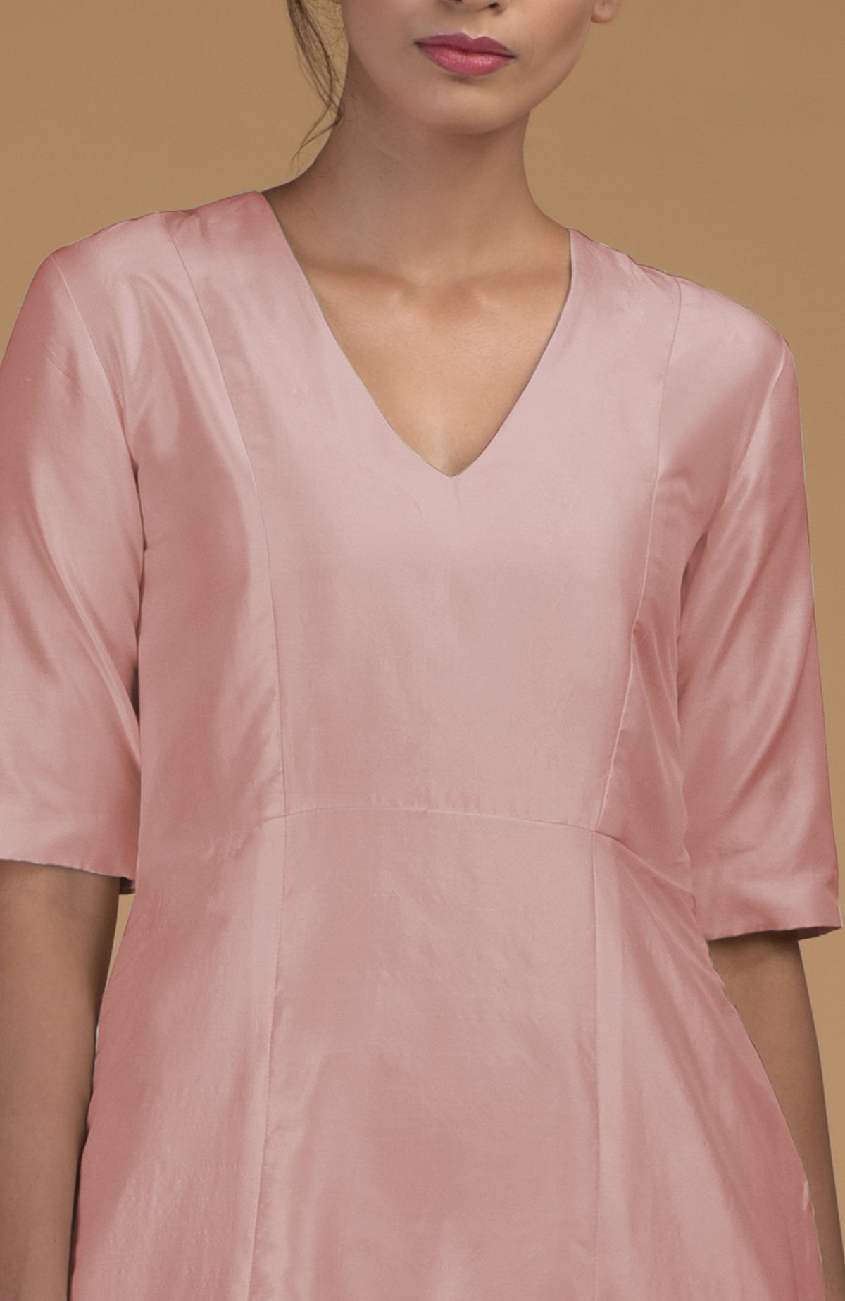 A woman models a rose beige pure Matka silk V-neck kali kurta with half sleeves.