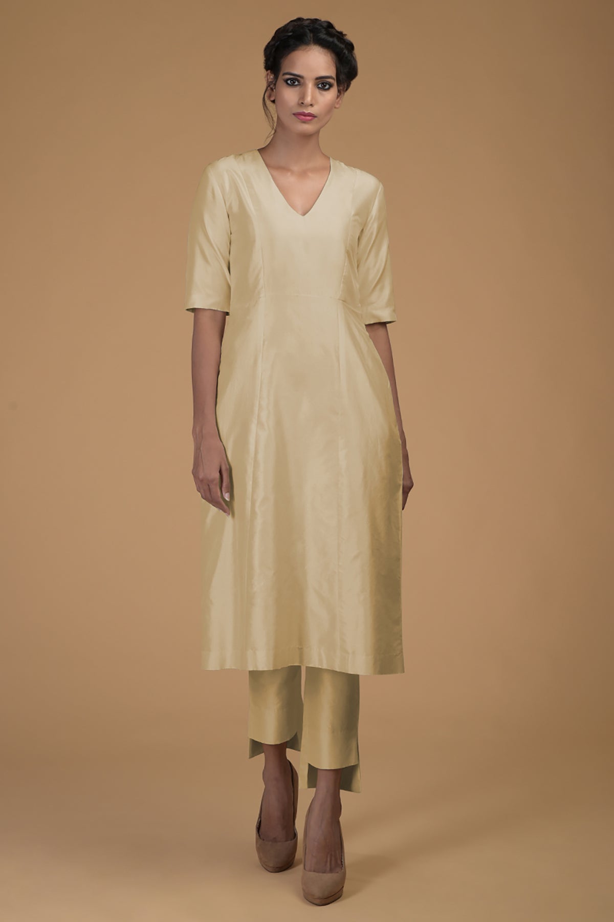 A woman models a beige pure Matka silk V-neck kali kurta set with slim pants.