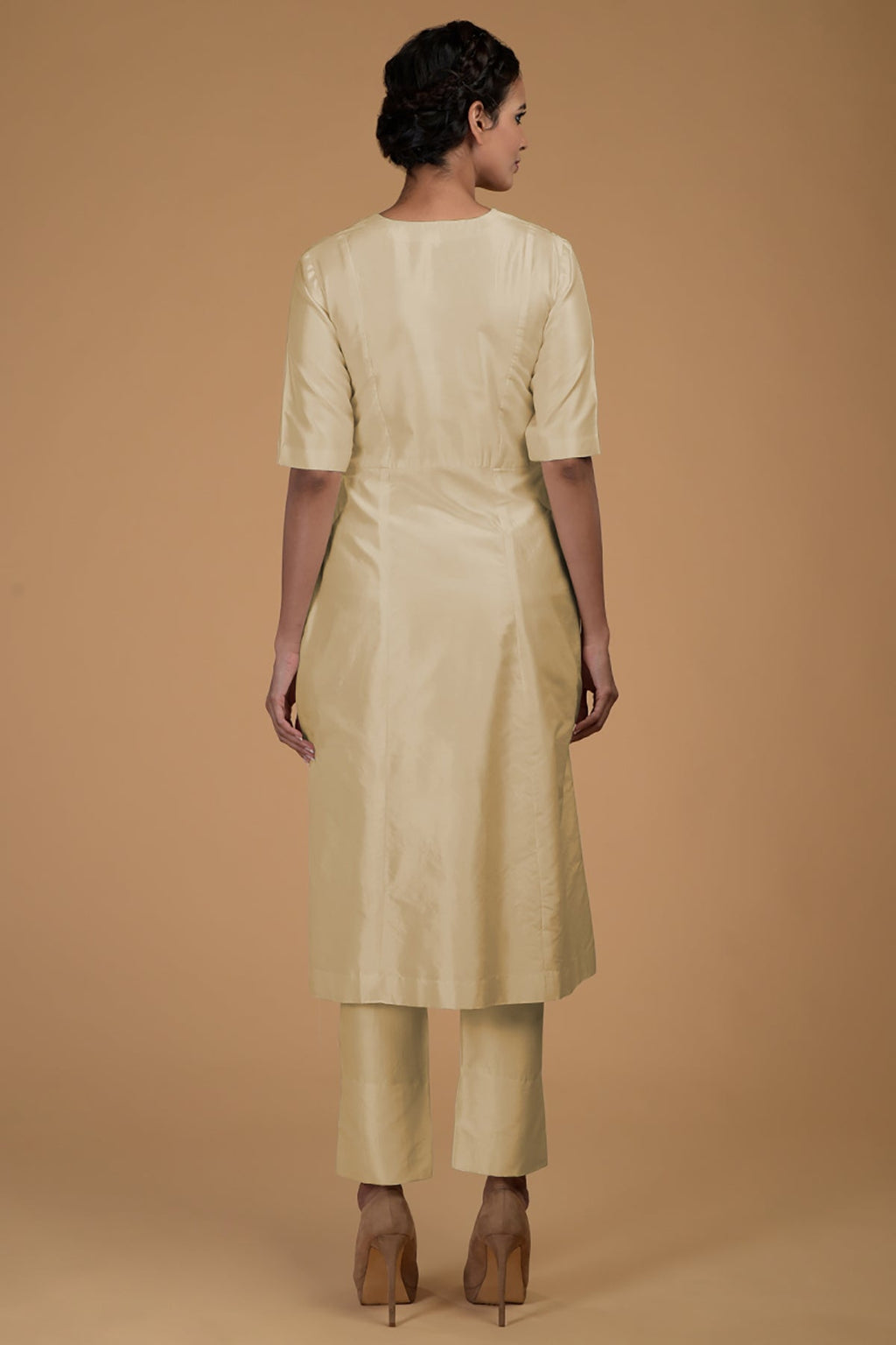 A woman from behind wearing a beige Matka silk V-neck kali kurta set.