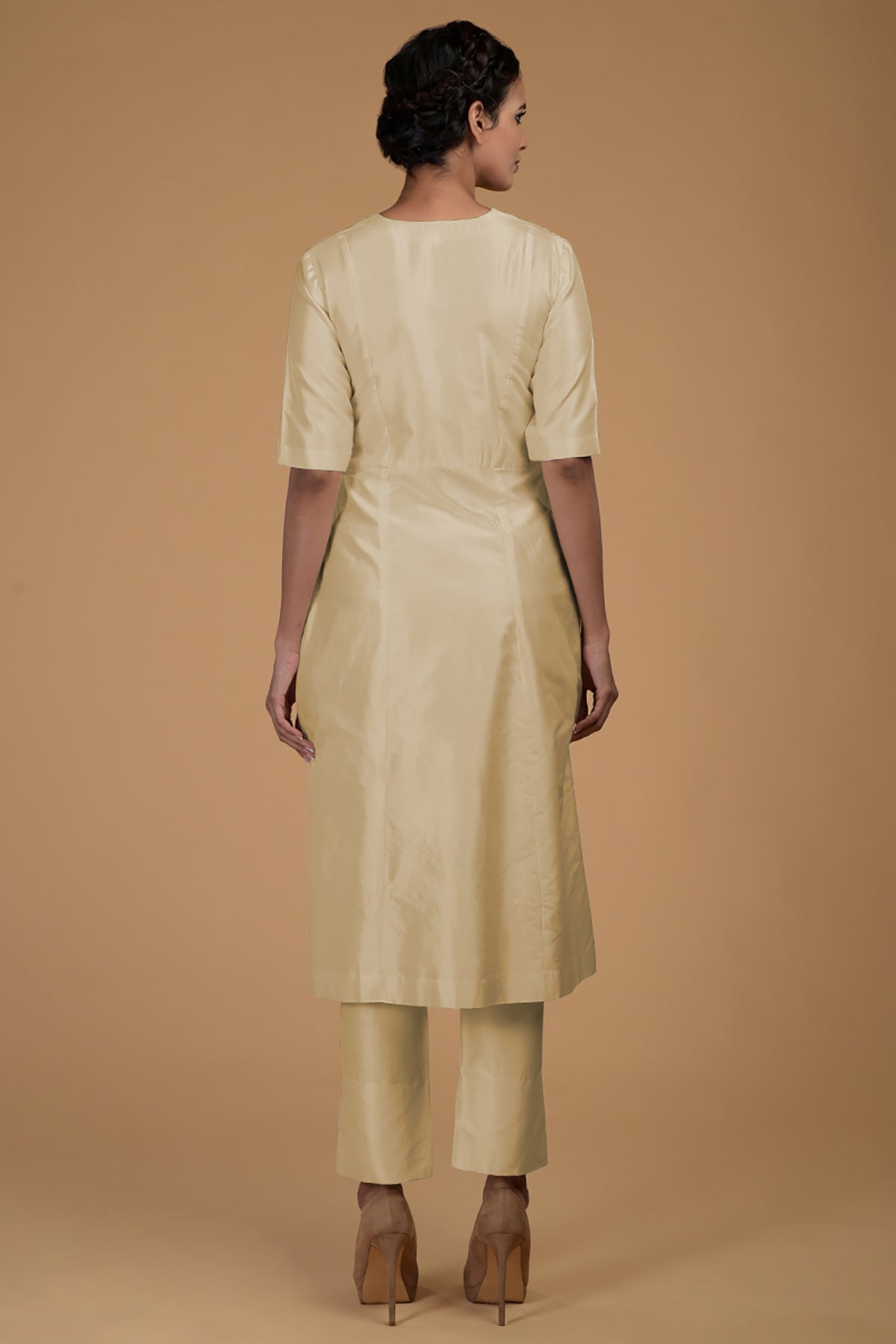 A woman from behind wearing a beige Matka silk V-neck kali kurta set.