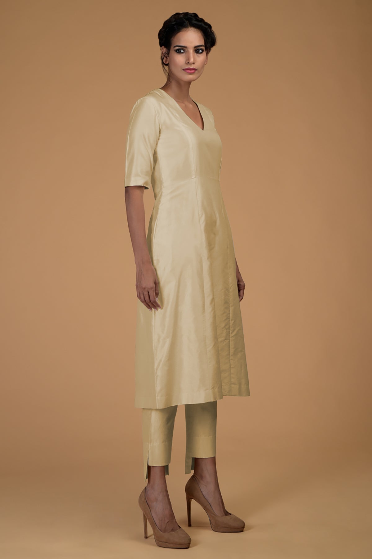 A woman models a beige pure Matka silk V-neck kali kurta set with slim pants.