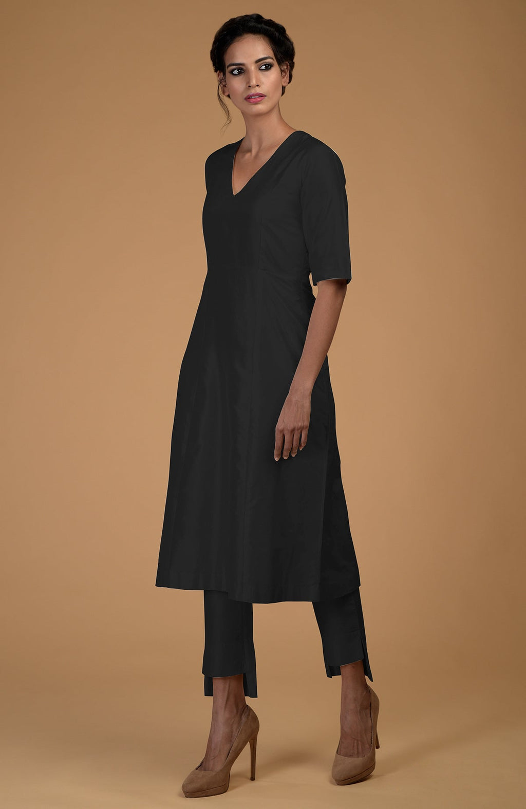 A woman models a black V-neck kali kurta and slim-fit pants with heels.