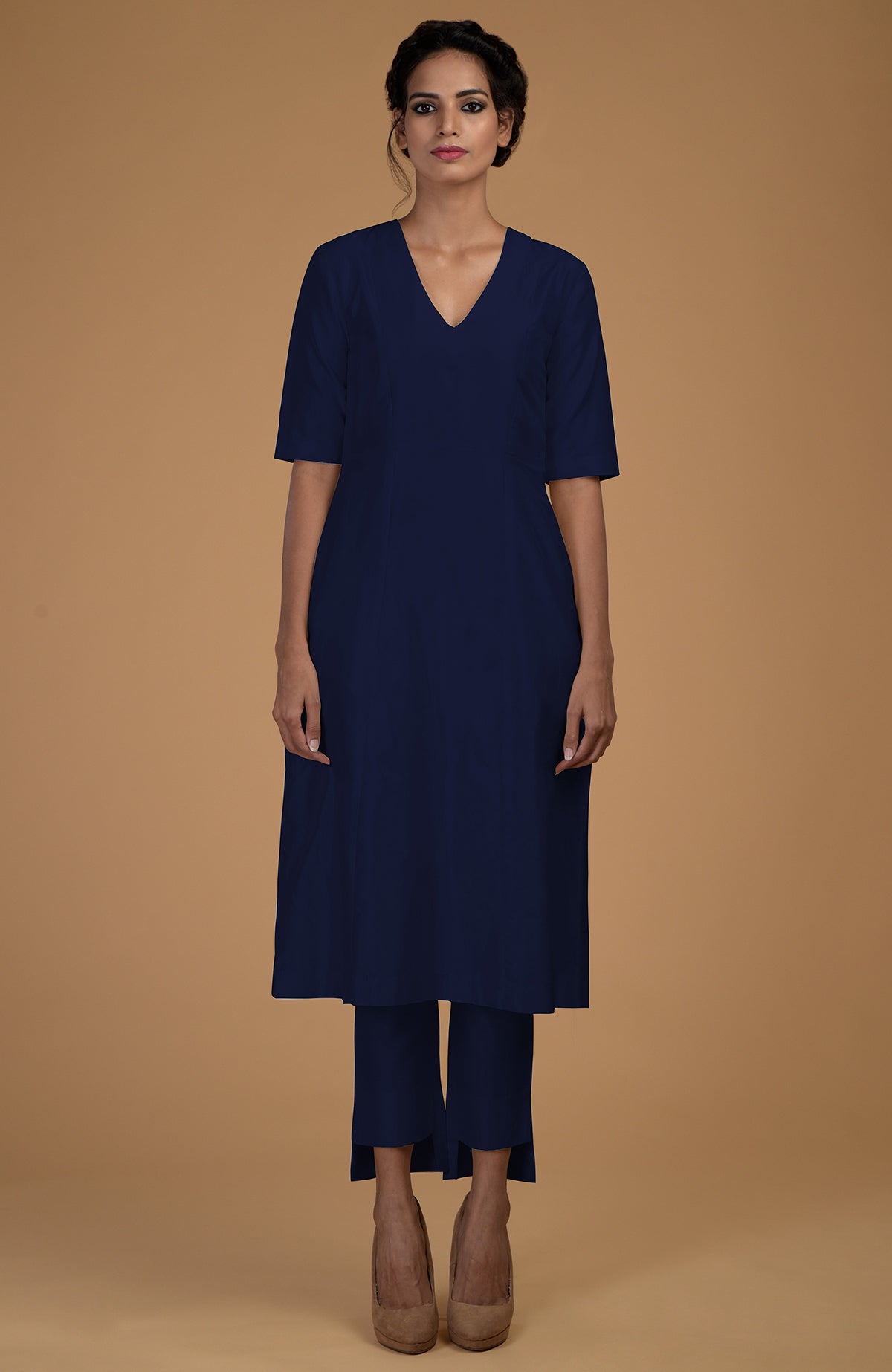 A woman models a navy blue V-neck kali kurta set with slim-fit pants.