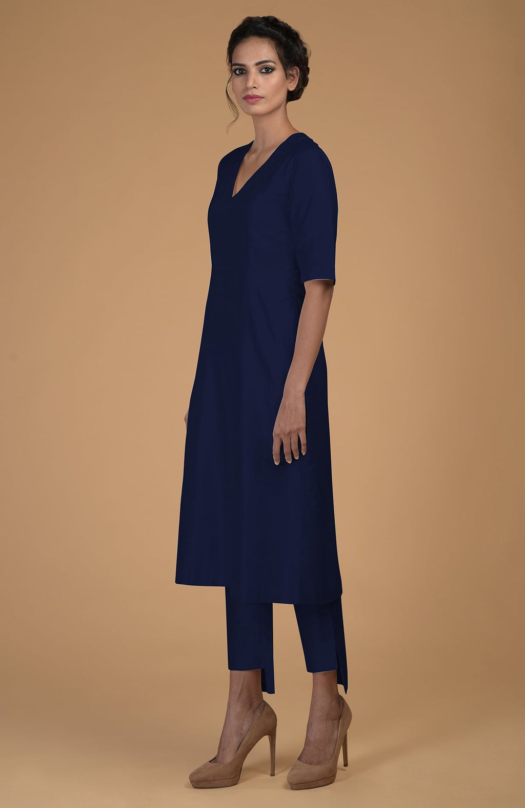 A woman models a navy blue V-neck kurta and slim-fit pants with asymmetric hems.