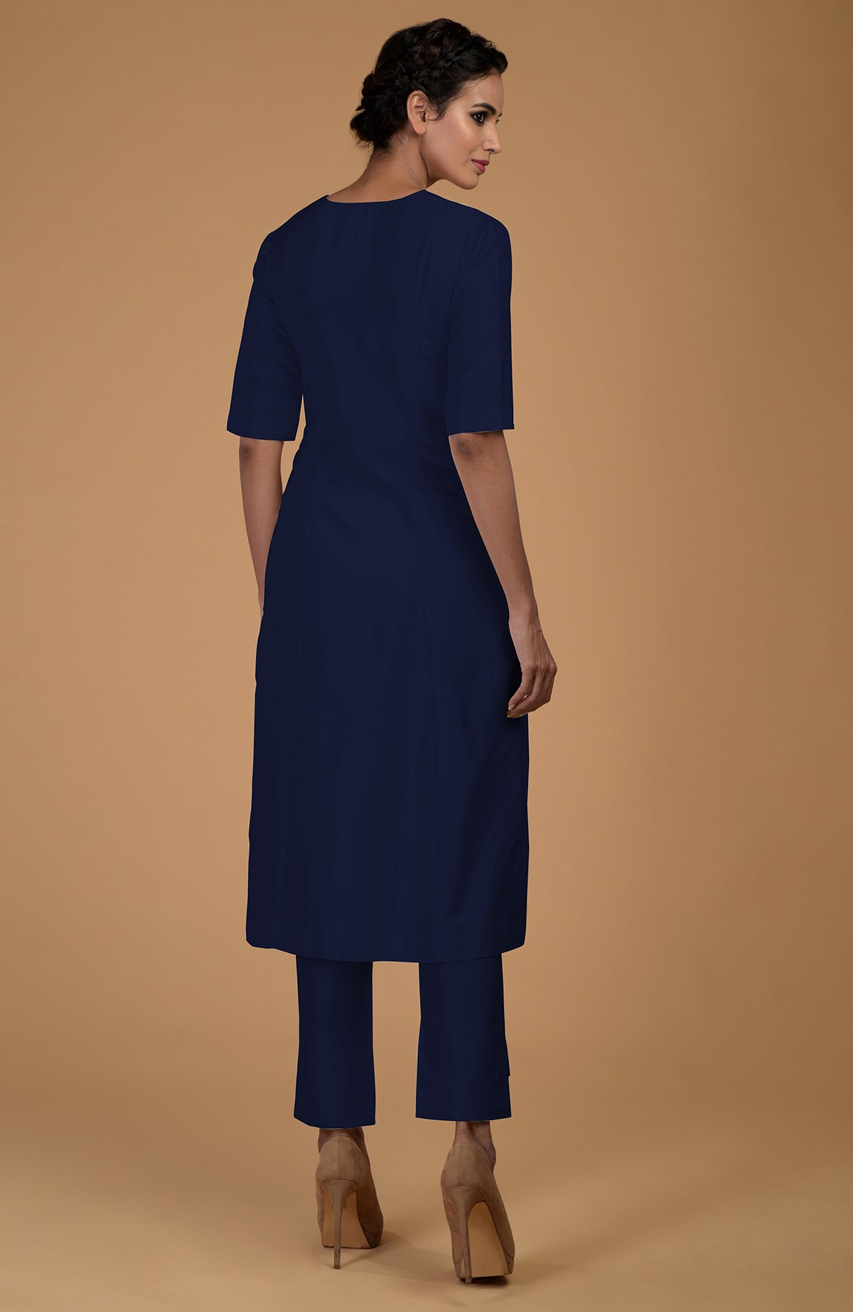 A woman models a navy blue V-neck kali kurta set with slim-fit pants.