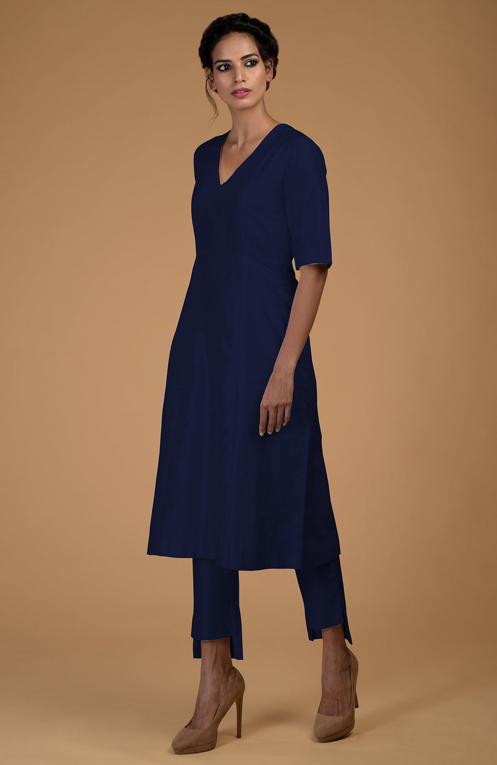 A woman models a navy blue V-neck kali kurta set with slim-fit pants.