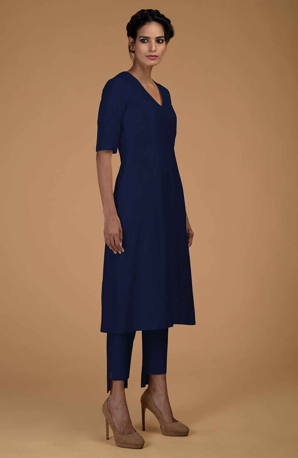 A woman models a navy blue V-neck kali kurta set with slim-fit pants and heels.