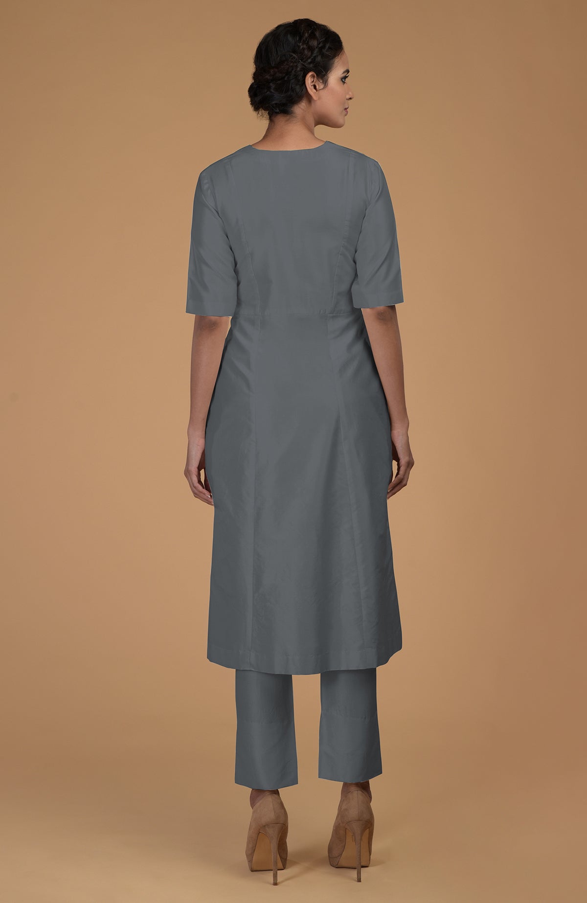 A woman from behind wears a grey V-neck kali kurta set with heels.