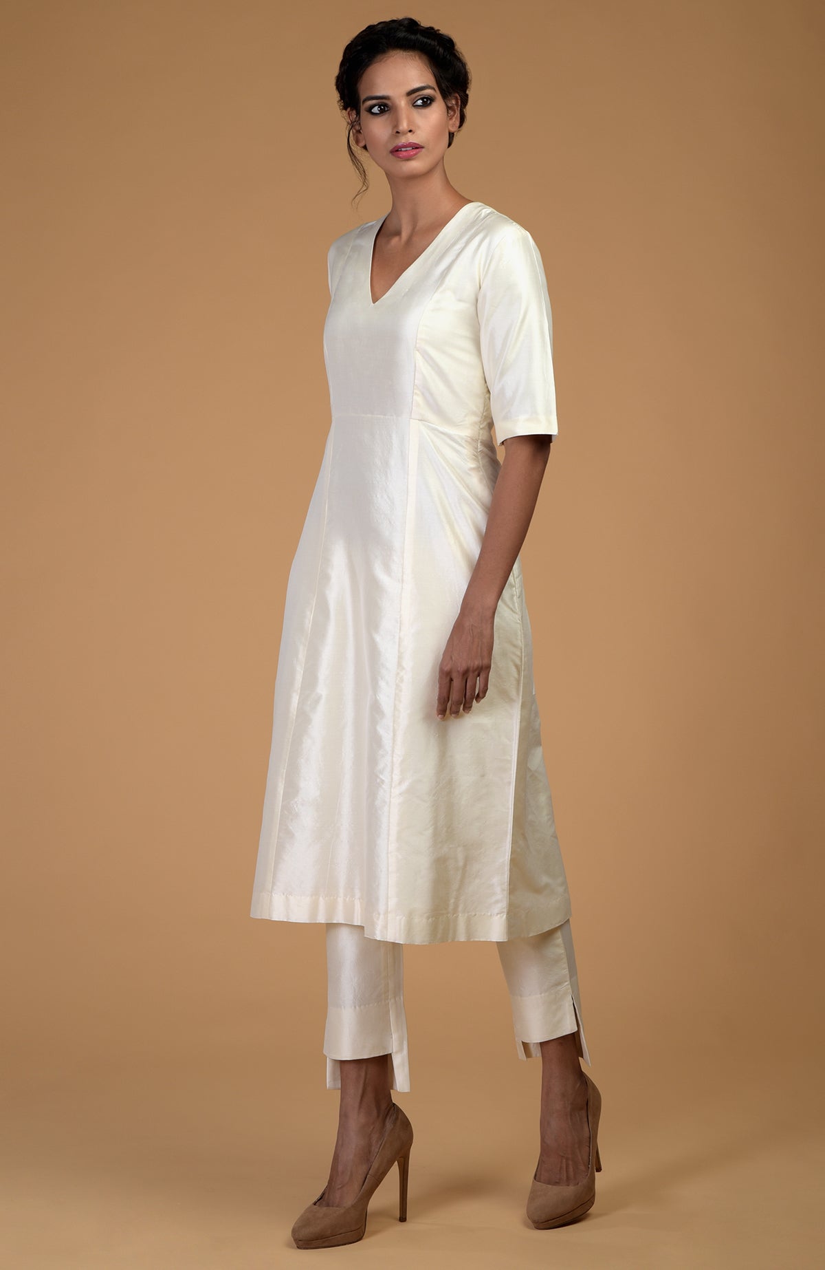 A woman models an ivory pure Matka silk V-neck kali kurta set.