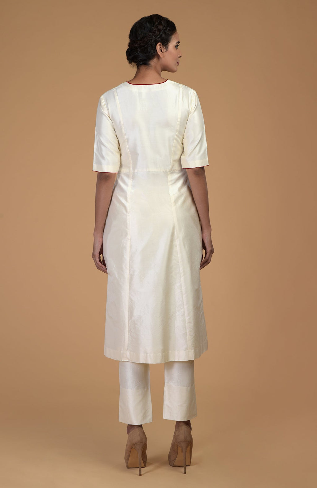 A woman models an ivory pure Matka silk V-neck kali kurta set with brown heels.