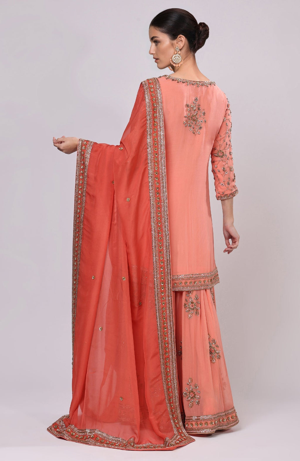A woman models a salmon dabka and zardozi hand-embroidered sharara set.