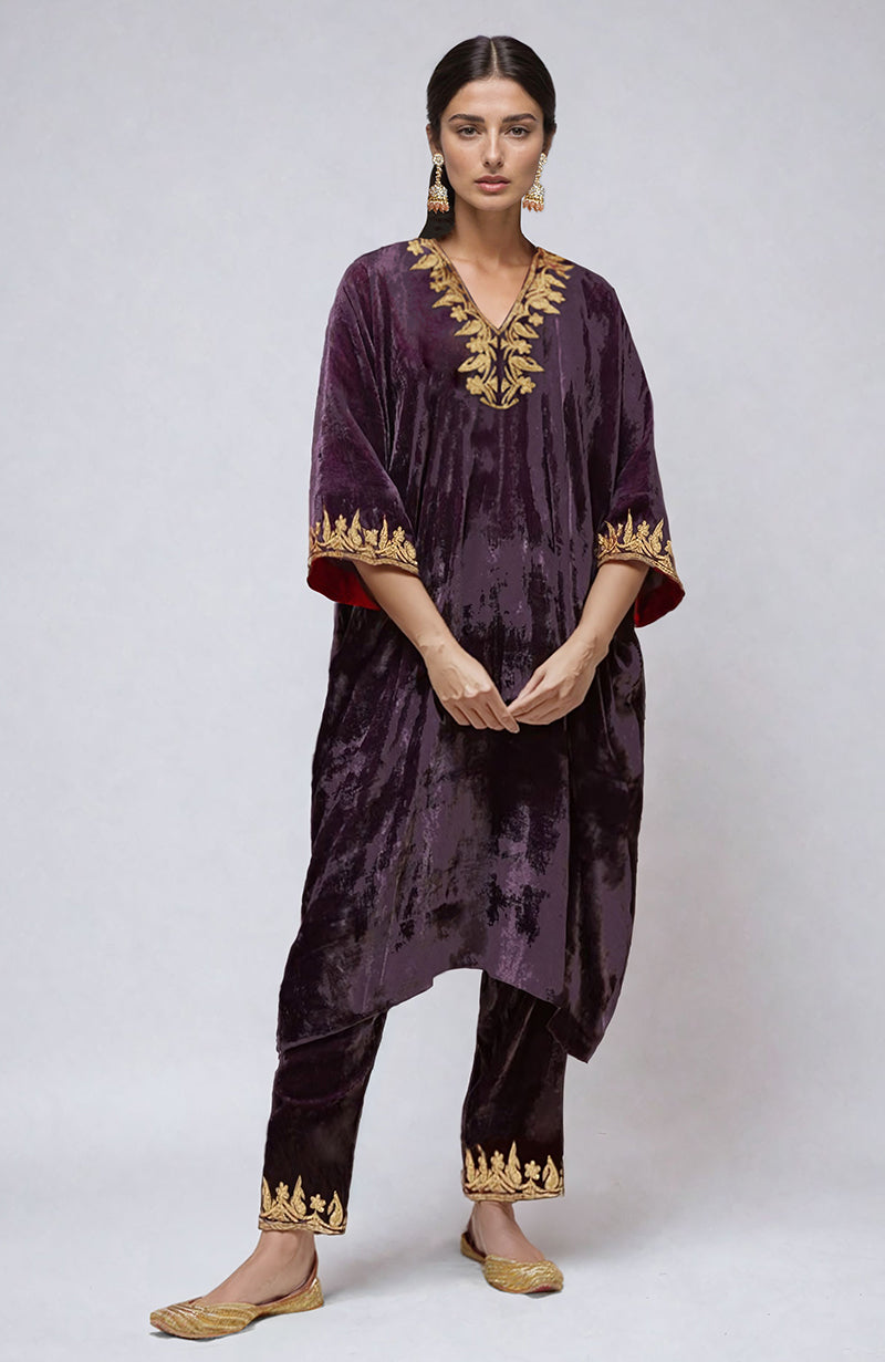 A woman models a mulled grape velvet kurta set with gold embroidery.