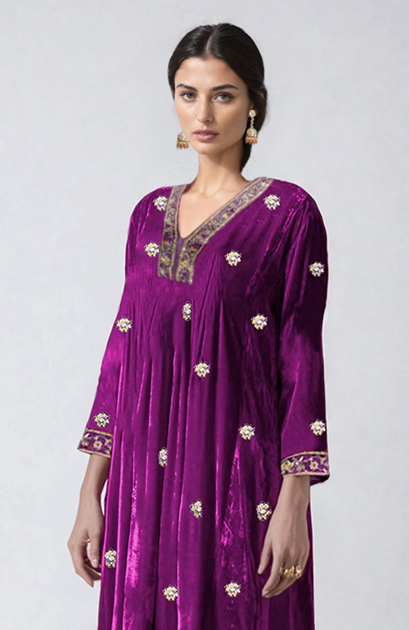 A woman models a berry velvet choga kurta with gold embroidery and sequin details.
