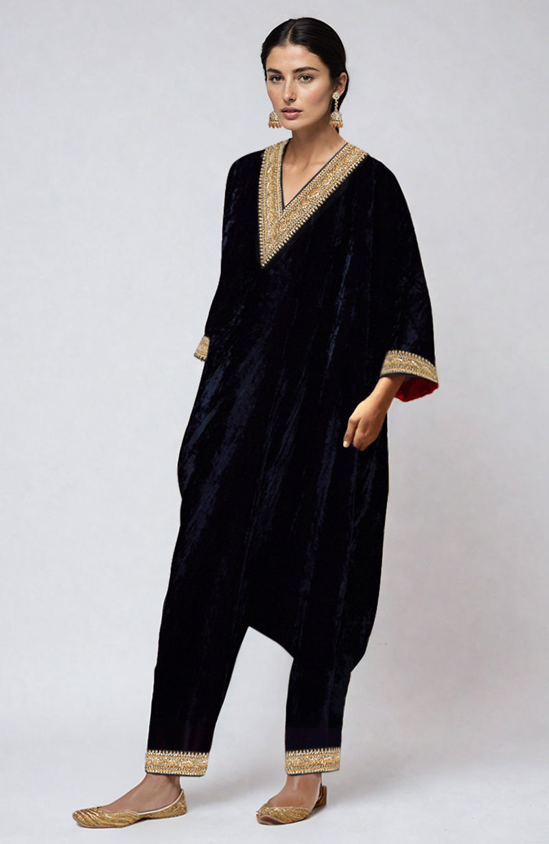 A woman models a midnight blue velvet kurta set with gold embroidery.