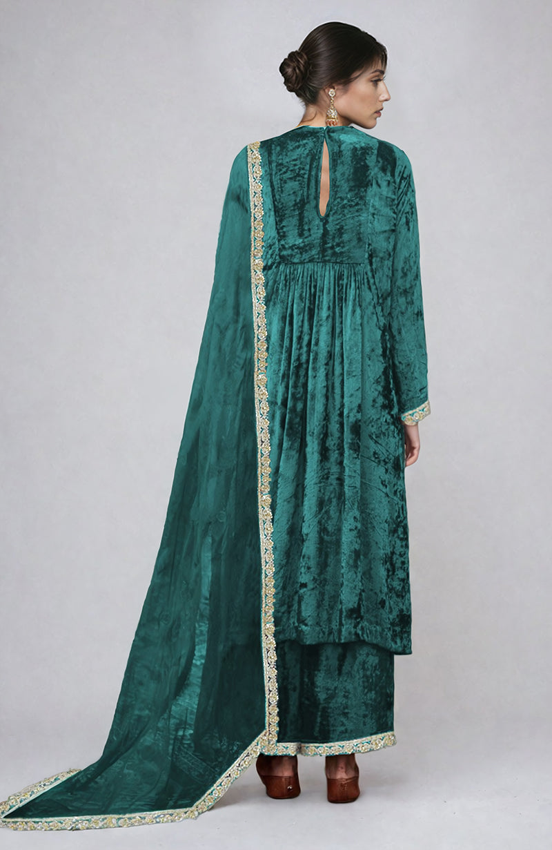 A woman from behind wears a green velvet kurta set with gold embroidery.