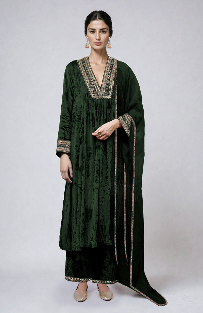 A woman models a dark green velvet kurta set with gold embroidery.