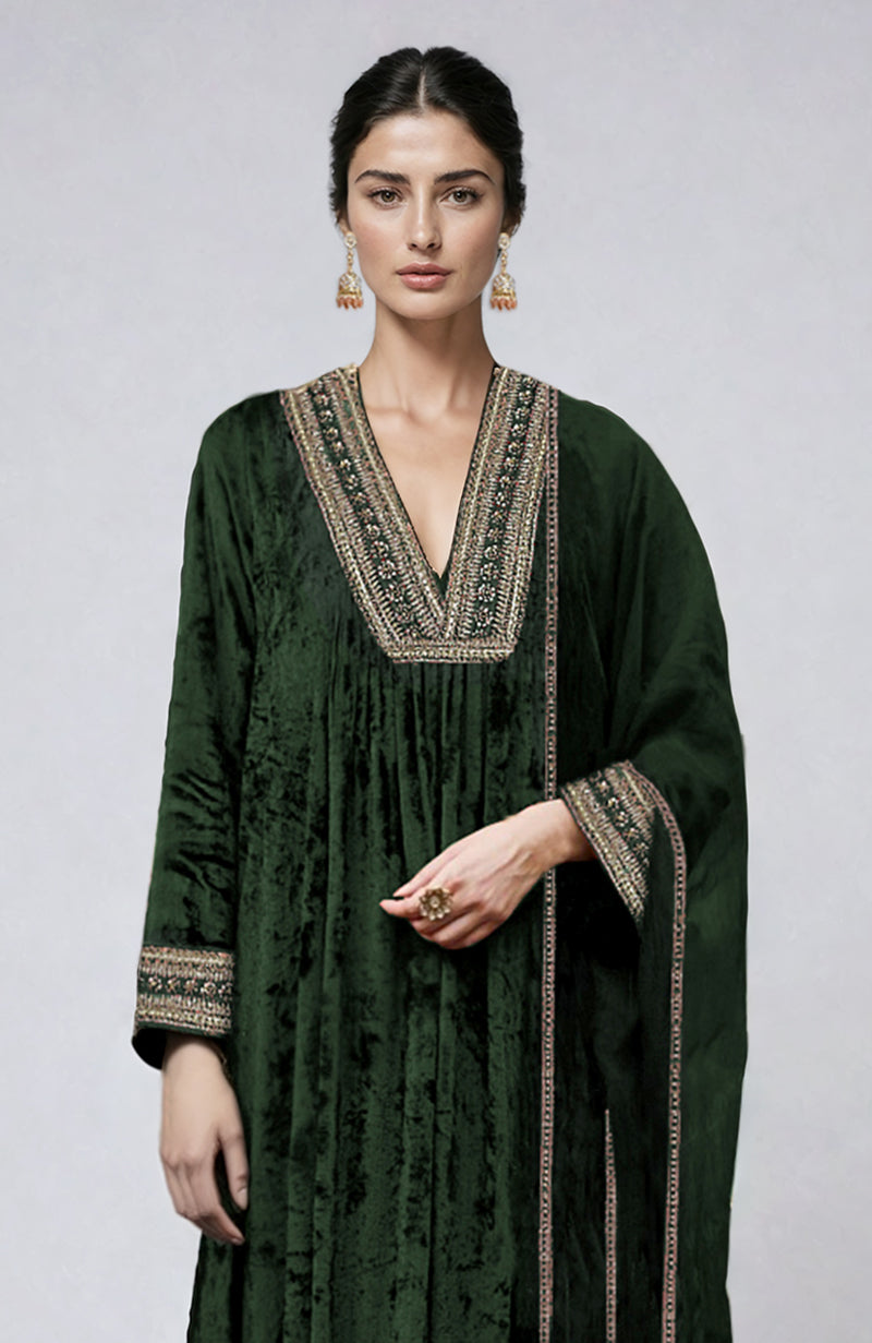 A woman models a bottle green velvet kurta set with gold zardozi embroidery.