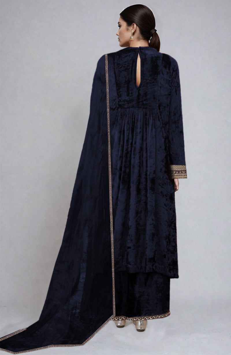 A woman models a midnight blue velvet kurta set with gold embroidery.