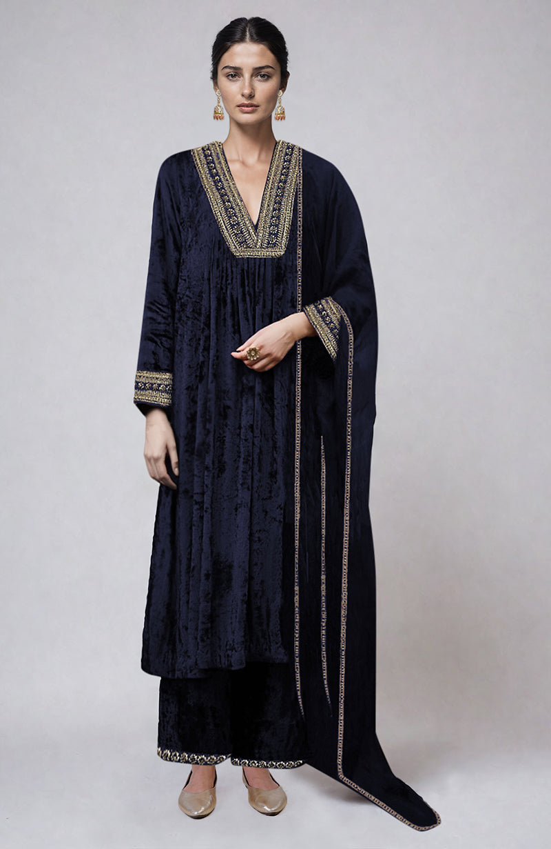 A woman models a navy velvet kurta set with gold embroidery.