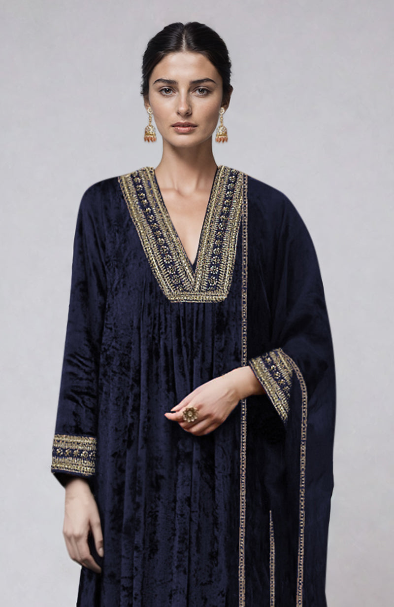 A woman models a midnight blue velvet kurta set with gold zardozi embroidery.