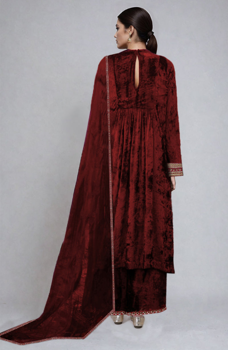A woman models a maroon velvet kurta set with gold embroidery.