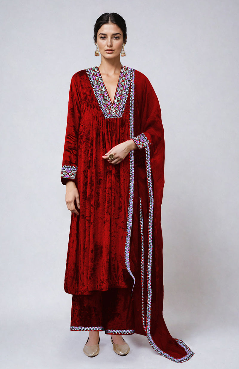 A woman models a red velvet kurta set with colorful embroidery.